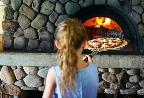 Un enfant faisant une pizza avec un four à bois