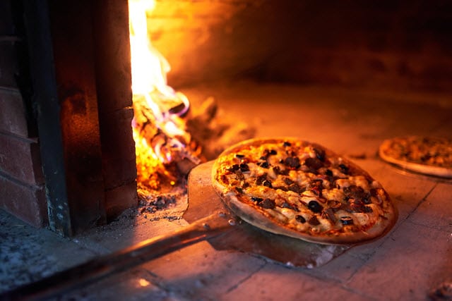 Des pizzas cuitent au feu de bois avec une cuisson convenable